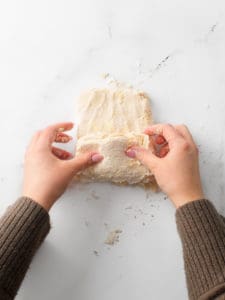 Using two hands to form the dough into a rough, rectangle and folding into thirds.