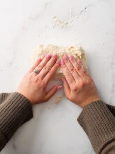 Using two hands to form the dough into a rough, rectangle and folding into thirds.