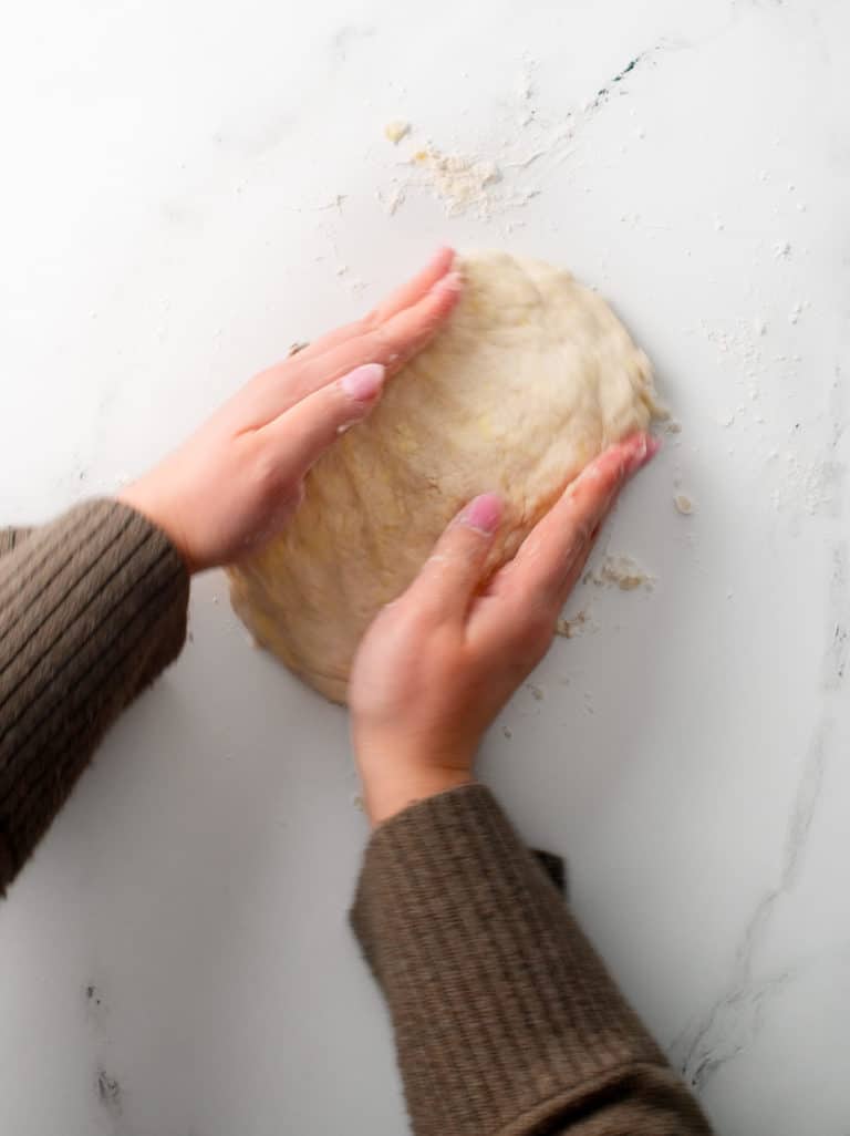 Using two hands to form the dough into a rough, rectangle and folding into thirds.