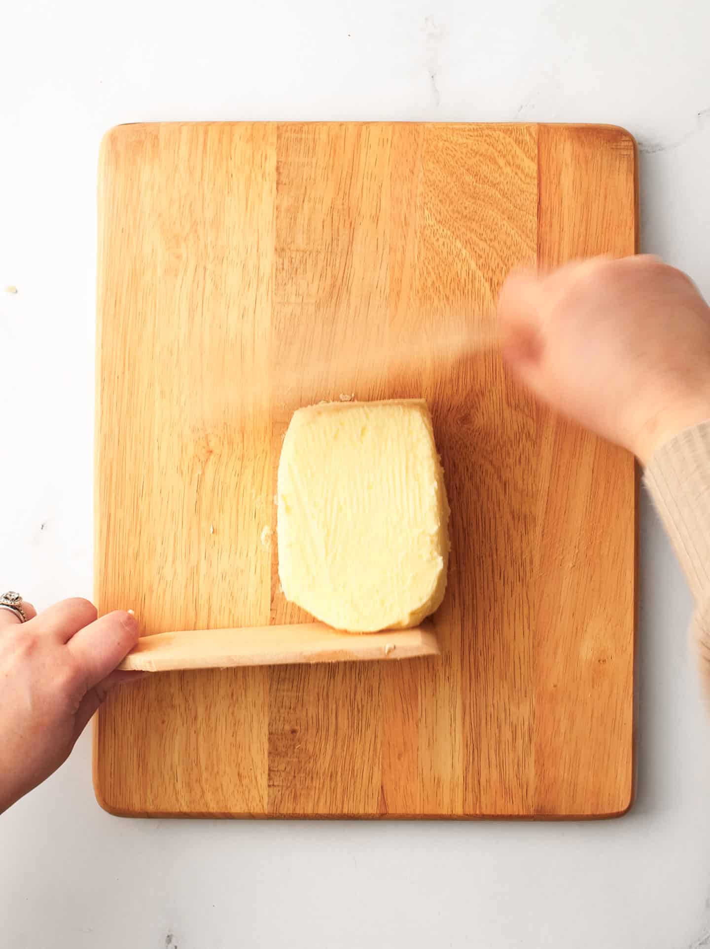 Both hands using wooden paddles to form and shape the butter.