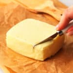 Butter block laying on parchment paper on a wooden board.