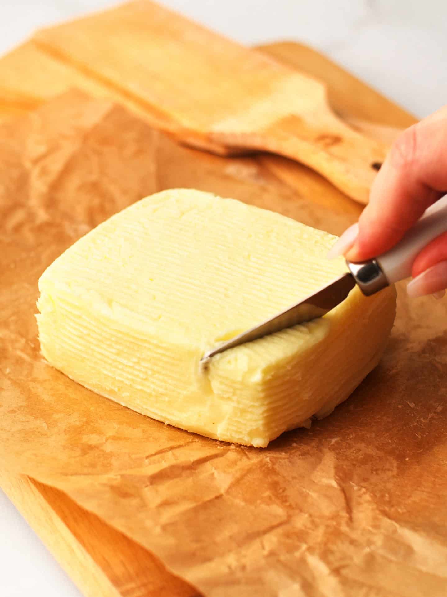 Butter block laying on parchment paper on a wooden board.