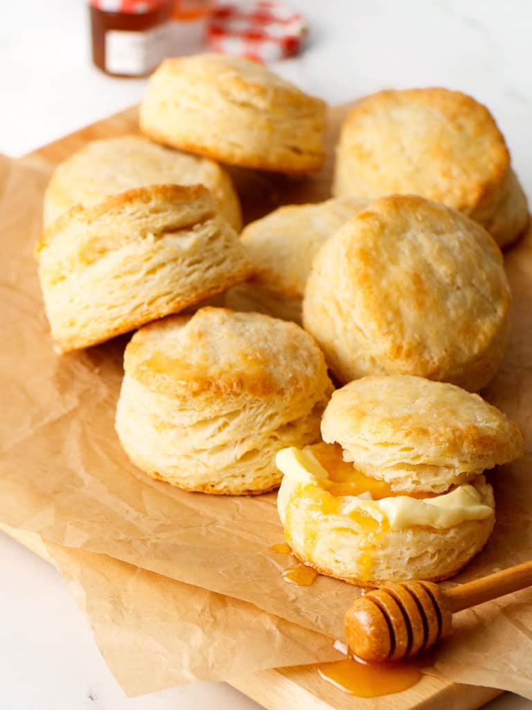 Butter Biscuits stacked with honeycomb drizzle on the side with butter.