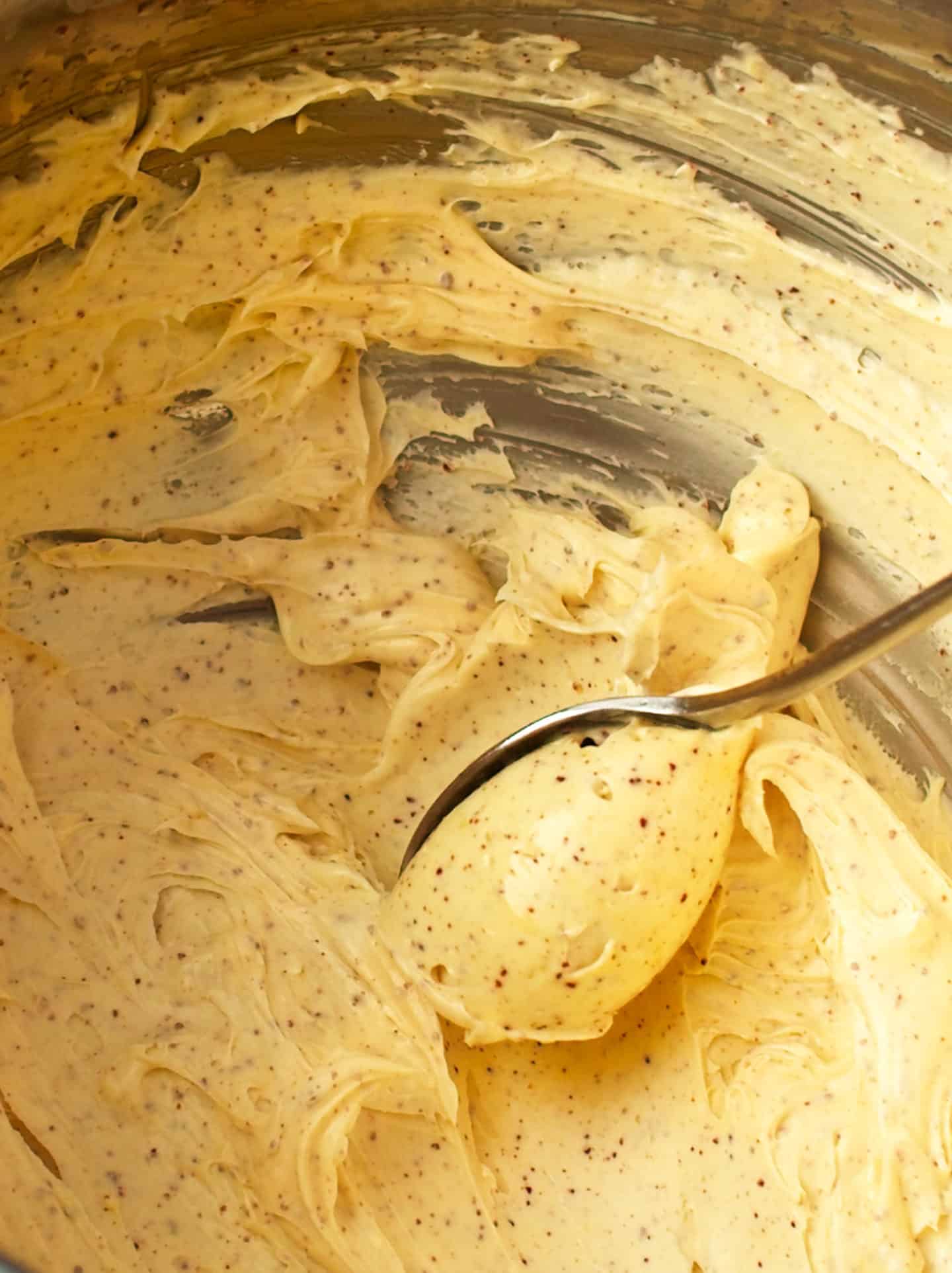 Whipped Brown Butter in metal bowl, swirling into a spoon.