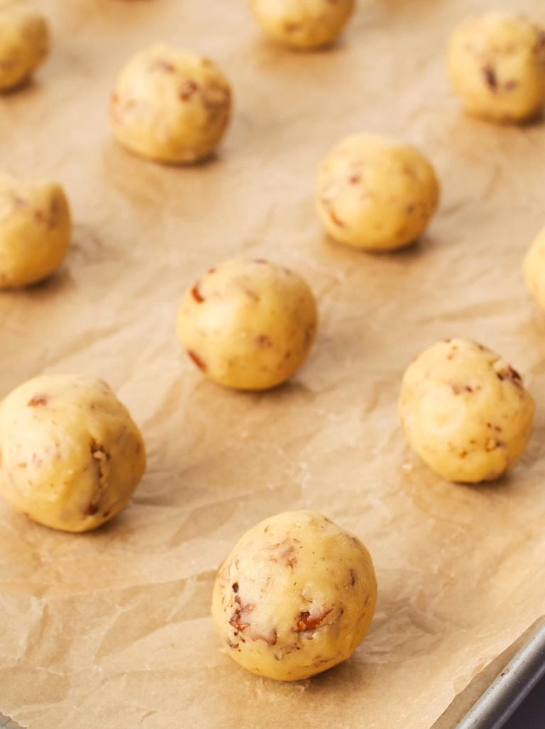 Cookie dough balls spaced out in a uniform line on a baking tray.