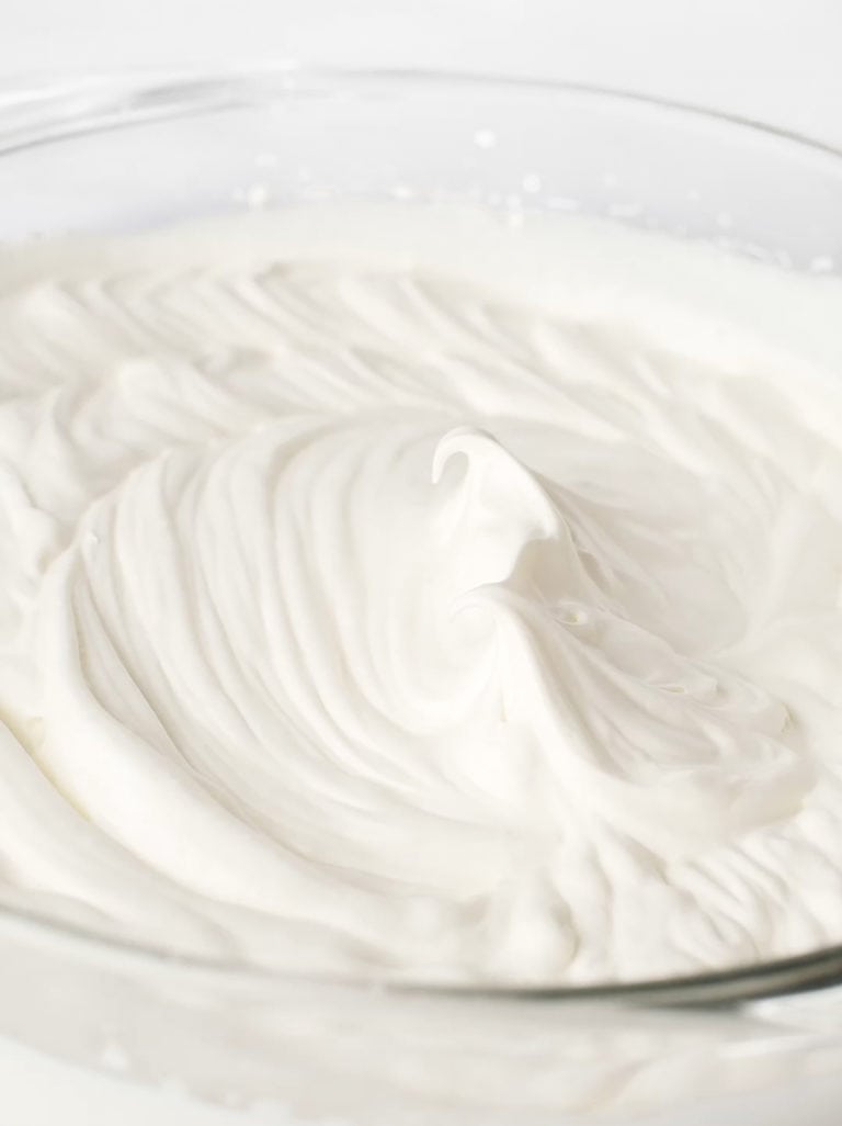 Whipped cream in a large, glass mixing bowl.