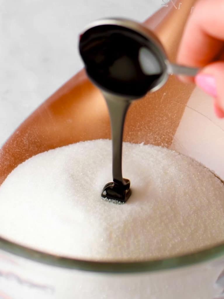 Adding sugar and molasses to a clear, glass stand mixer bowl.