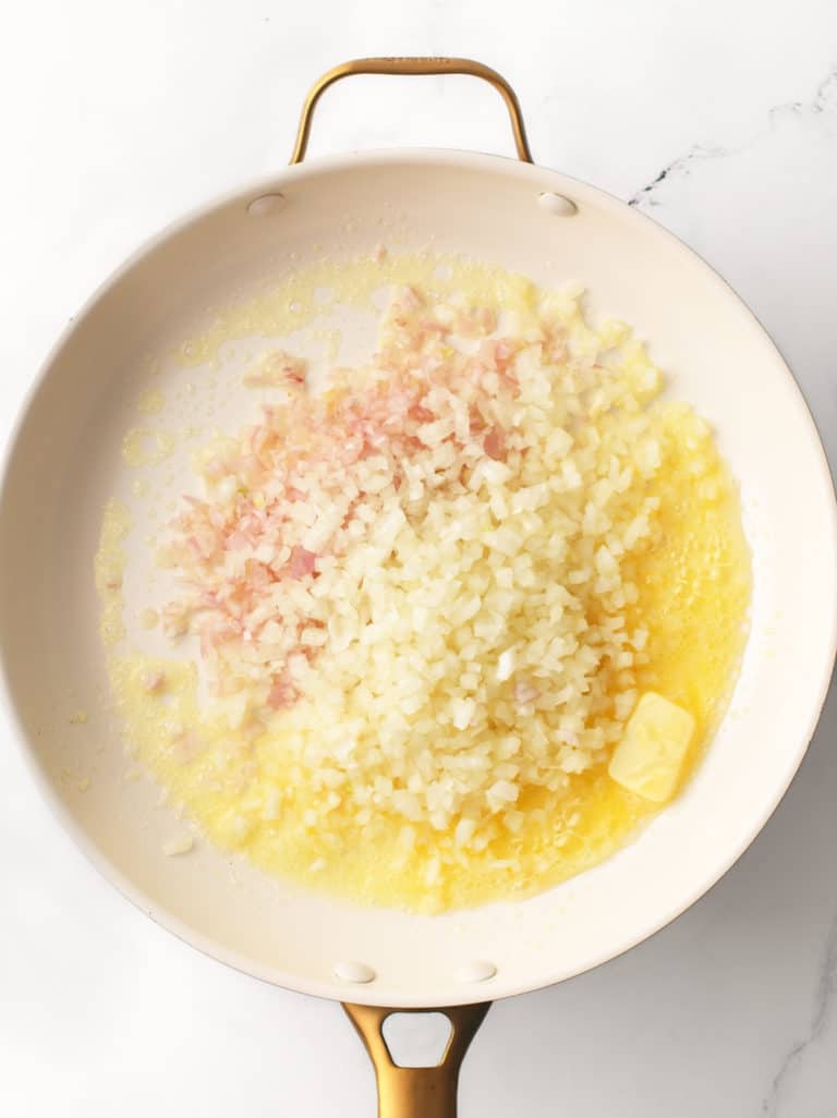 Shallots, onions, butter and garlic cooking in a large pan.