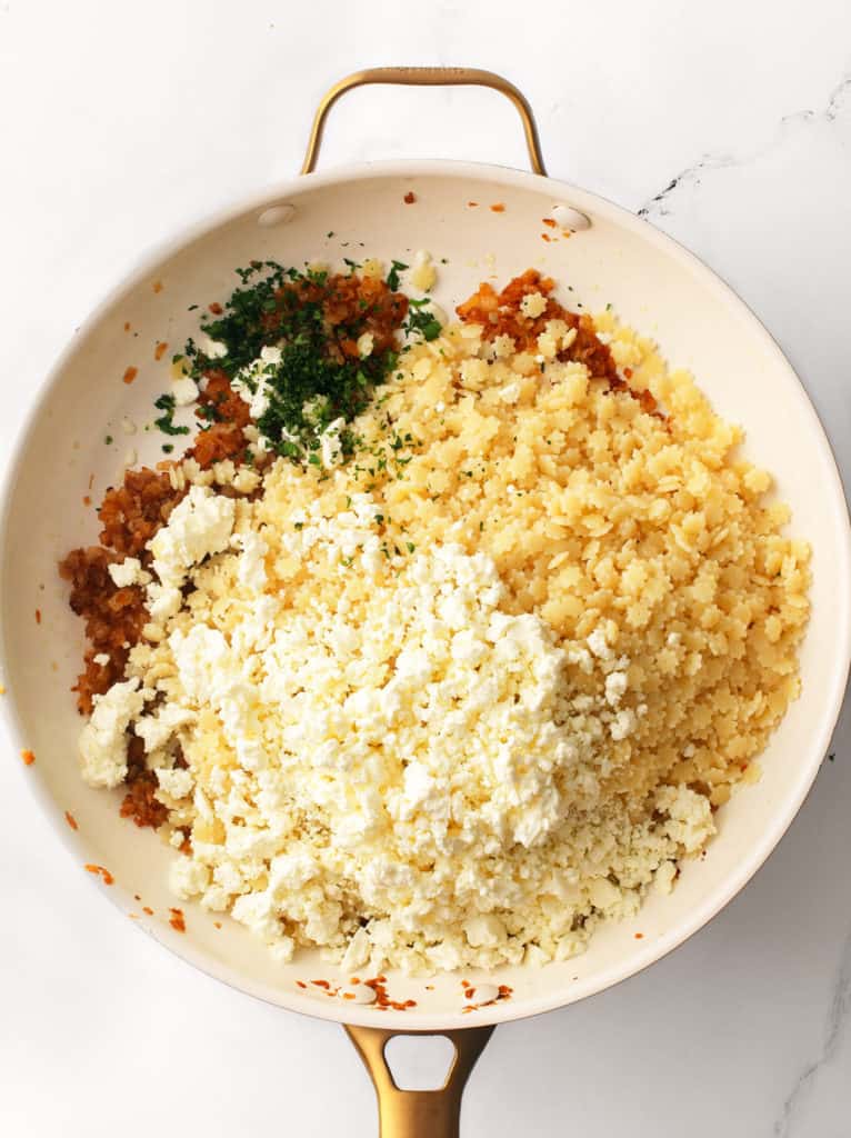 Caramelized onions, feta crumbles, parsley and cooked pasta in a large pan.