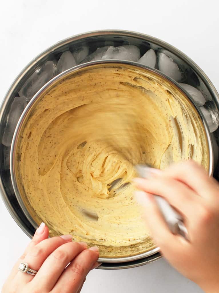 Using a whisk to whip melted brown butter in a smaller bowl over a larger bowl of ice.