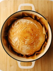 Golden baked artisan bread inside Dutch oven.