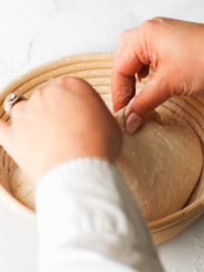 Using two hands to form the dough into a rough, round ball.