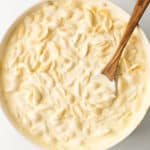 Creamy Alfredo Pasta in large cooking pan with a wooden spoon.