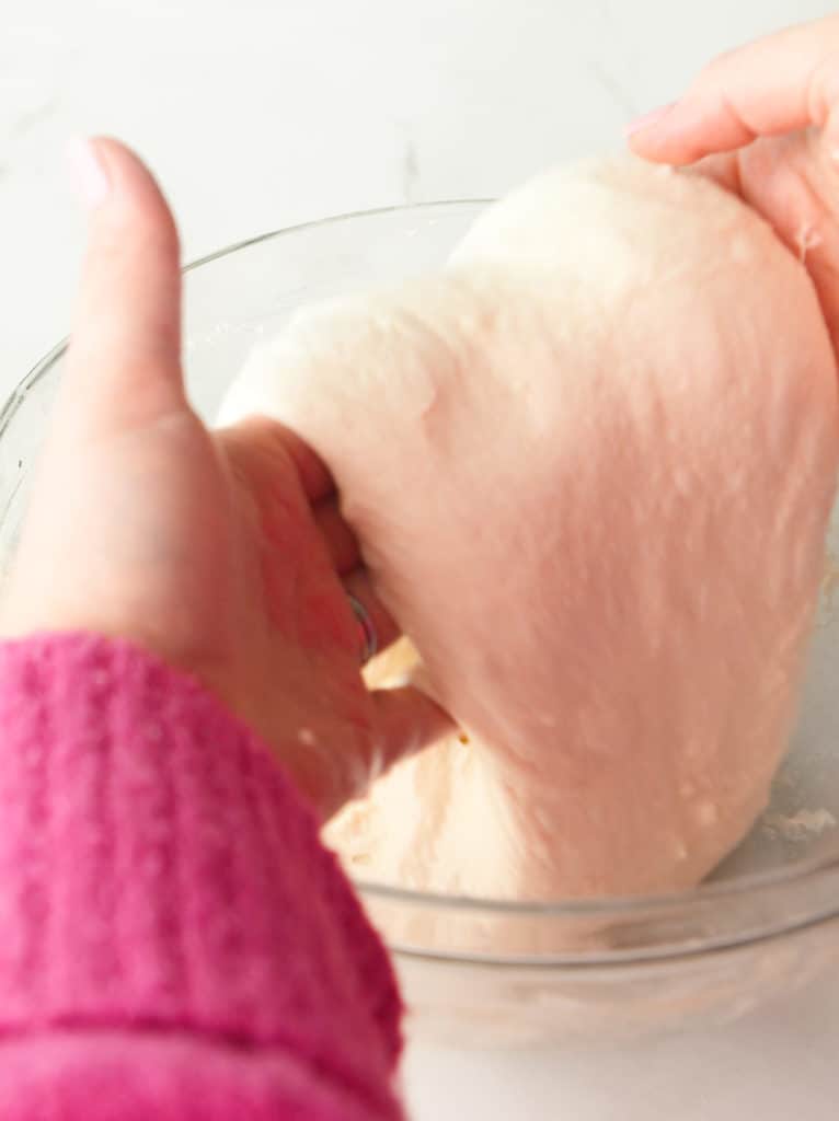 Using both hands to lift the dough and coil.