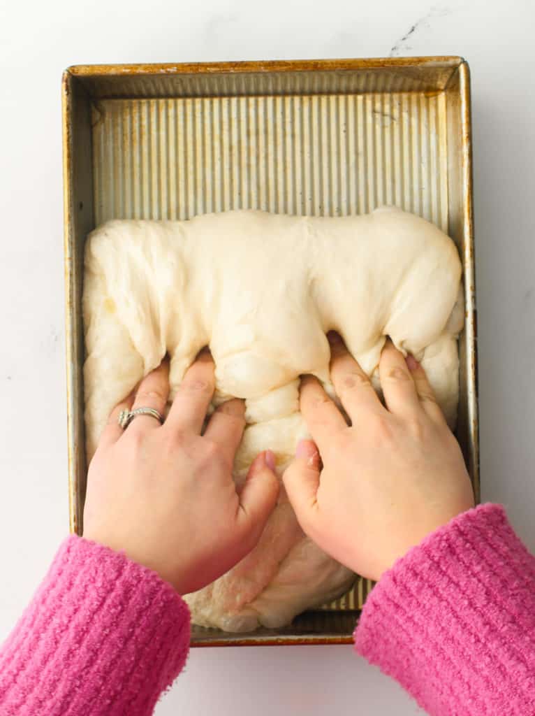 Using both hands to fold the dough into thirds.