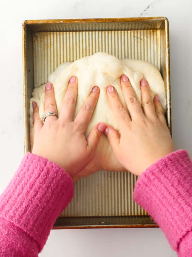 Using both hands to fold the dough into thirds.