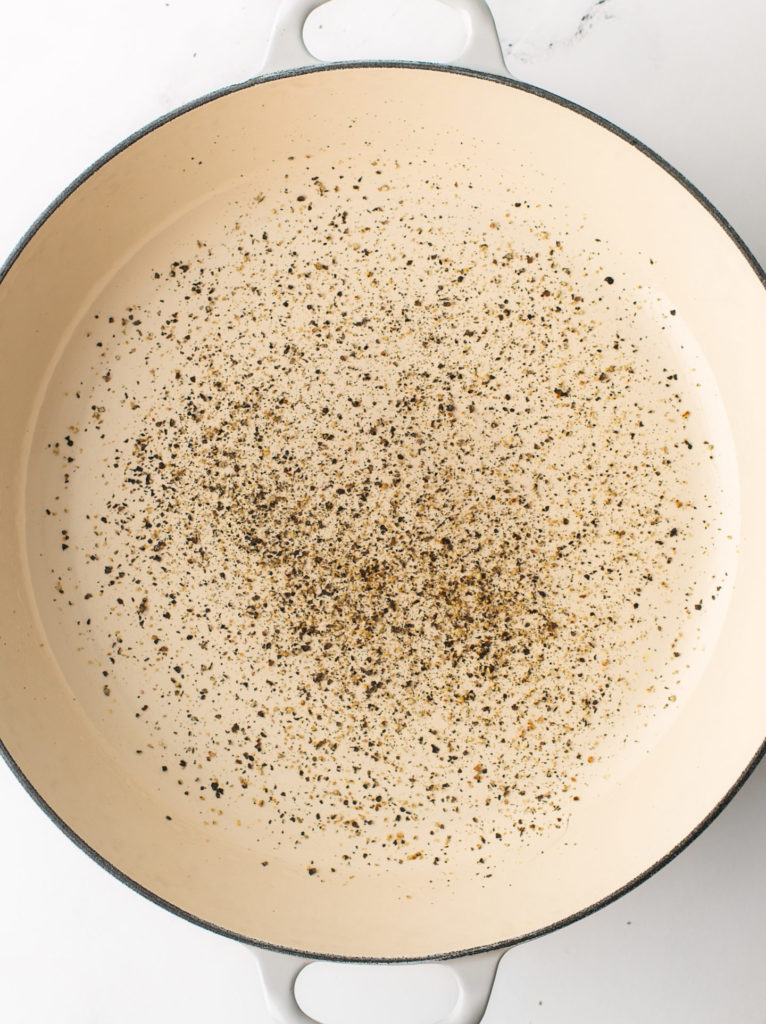 Cracked black pepper toasting on cooking pan.