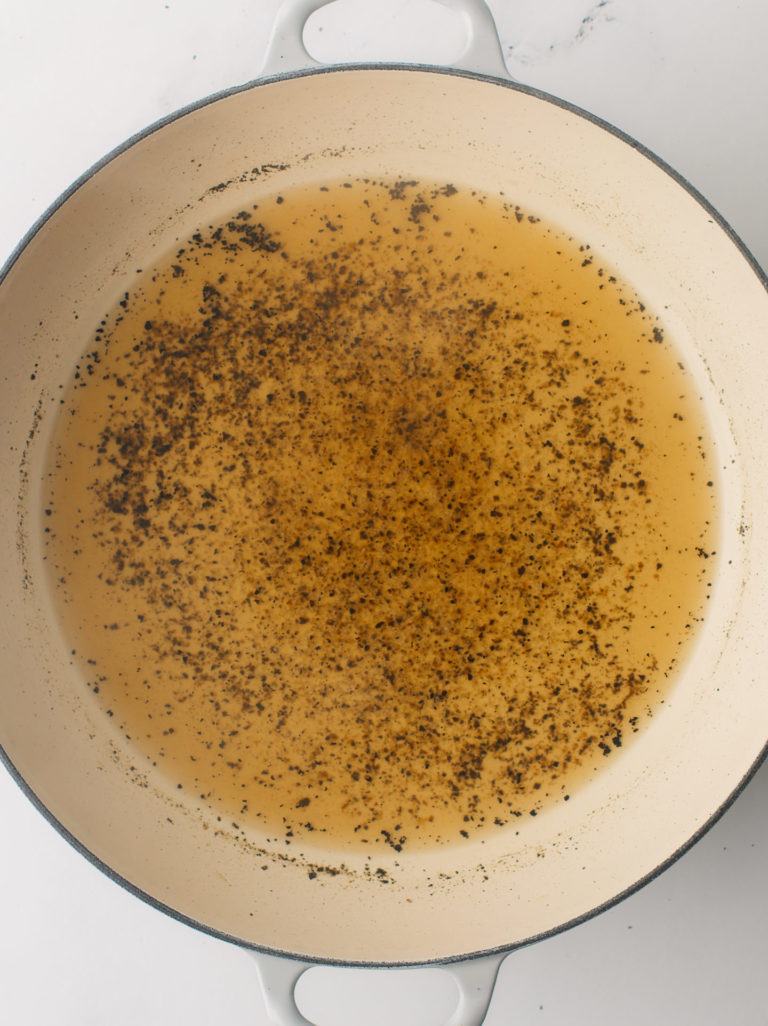 Water and cracked pepper simmering in cooking pan.