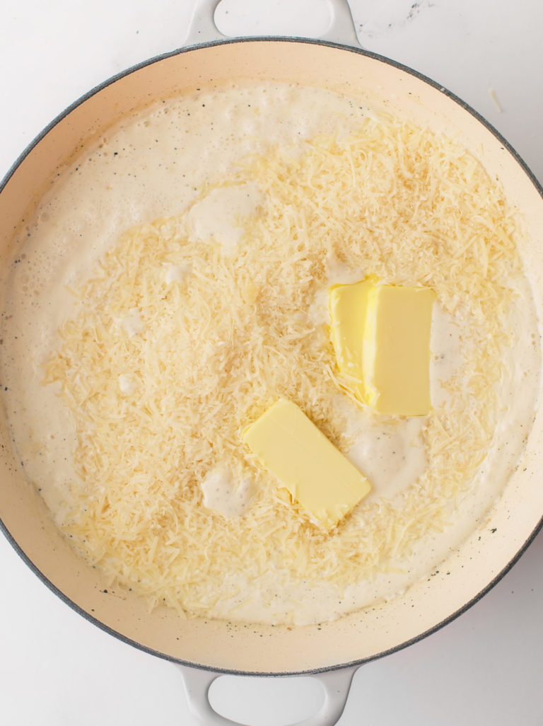 Heavy cream, butter and grated cheese simmering in cooking pan.