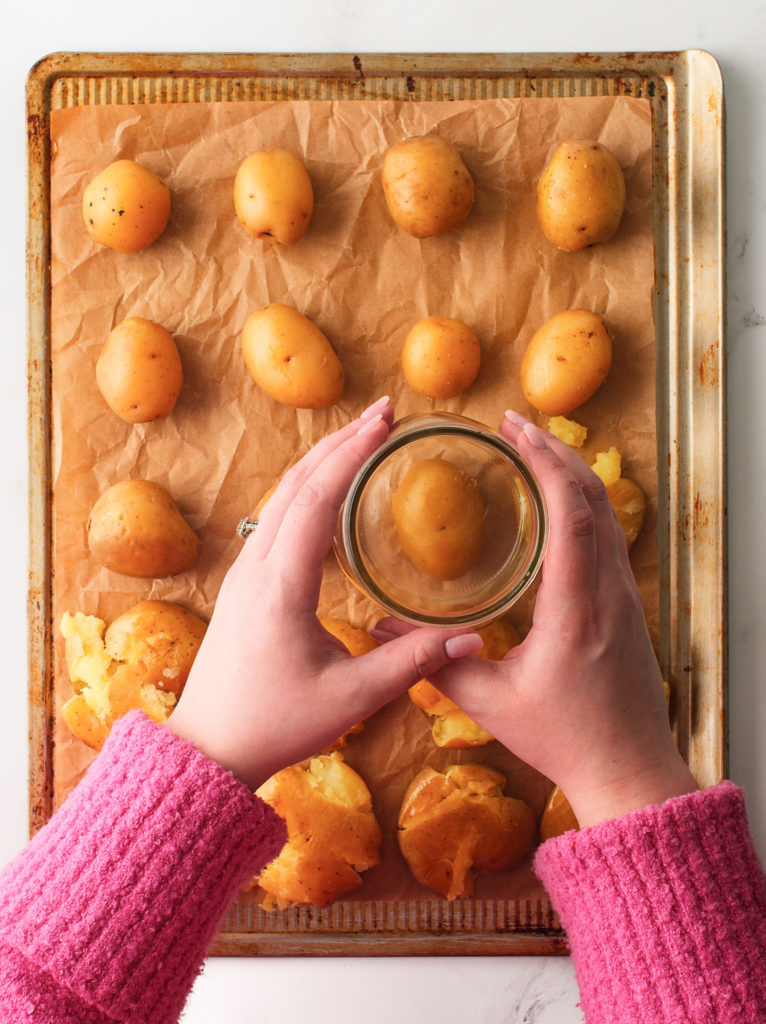 Smashing potatoes flat with a glass cup.