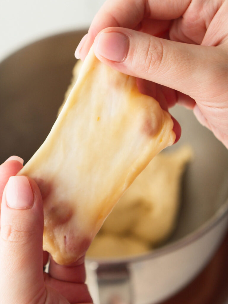 Enriched brioche dough being stretched to test elasticity.