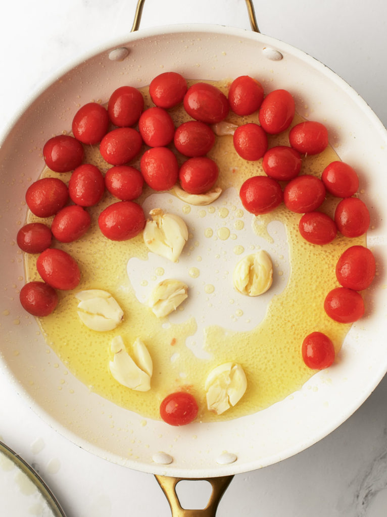 Cherry tomatoes and garlic cloves in large pan.