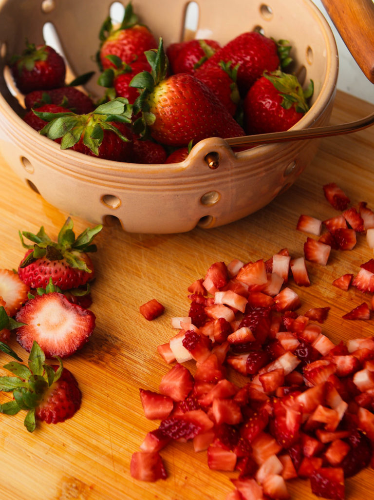Diced strawberries on wooden cutting board.