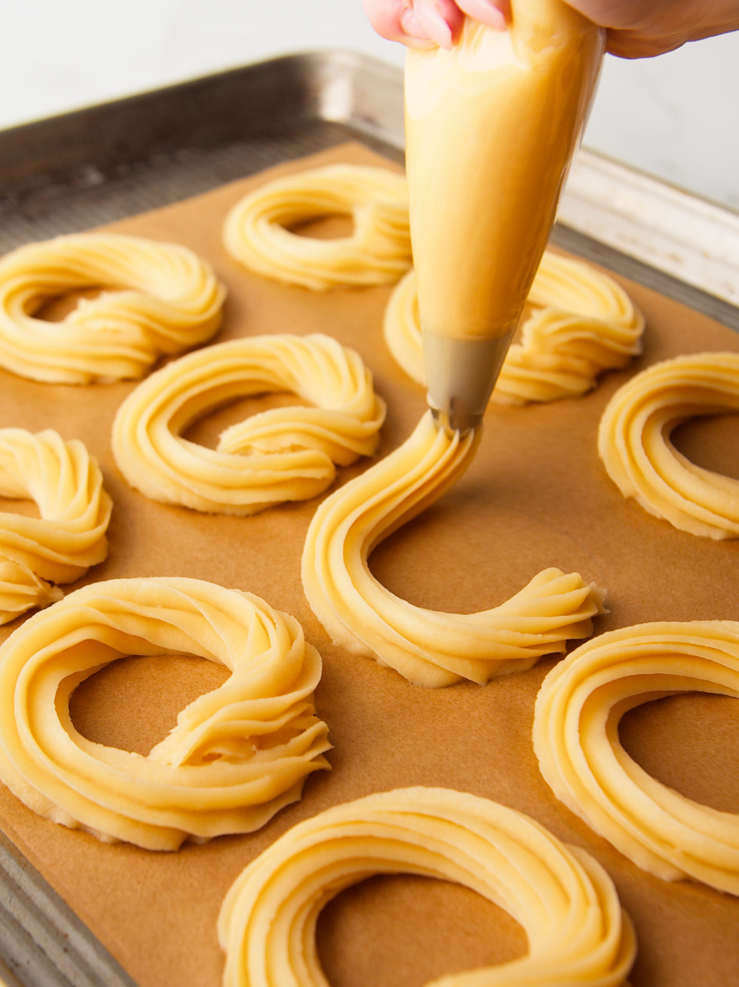 Piping donuts onto parchment paper.