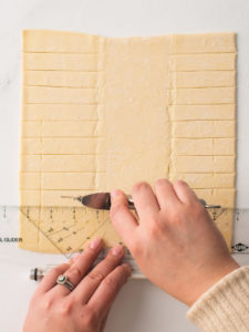 Cutting strips on each side of puff pastry sheet.