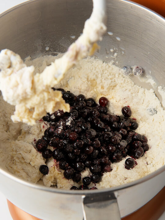 Dry ingredients in stand mixer with frozen blueberries.