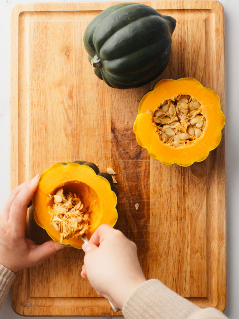 Deseeding acorn squash with a spoon.