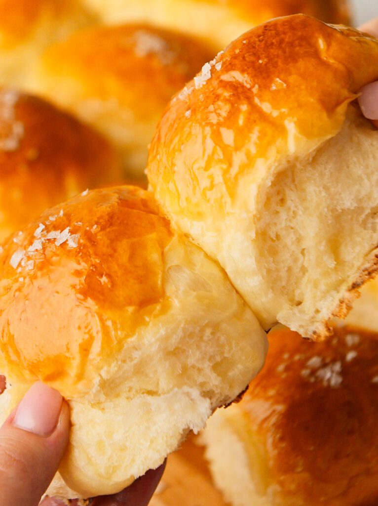 Two dinner rolls being pulled apart.