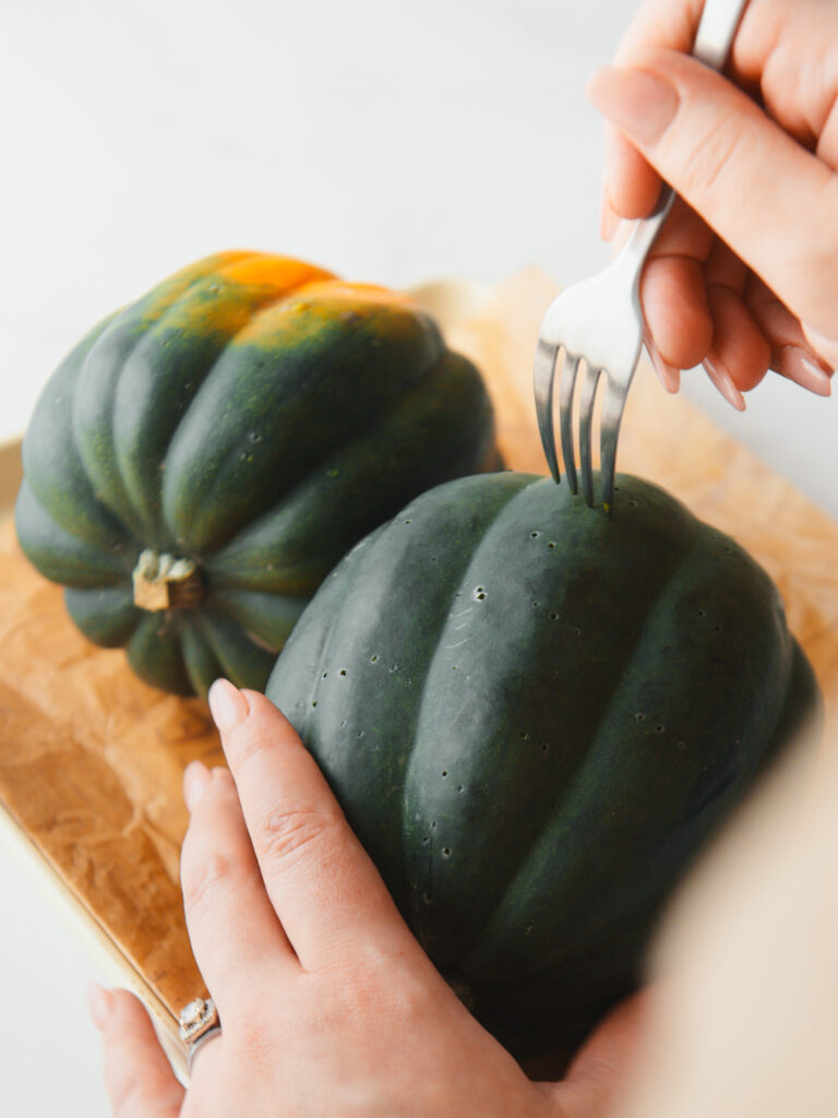 Piercing the outside of acorn squash with a fork.