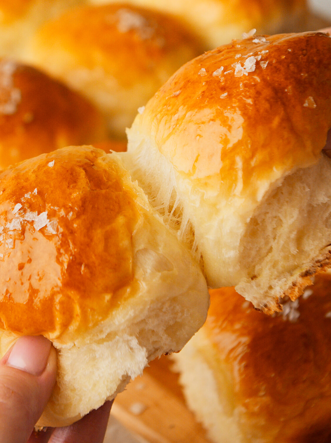 Two dinner rolls being pulled apart.