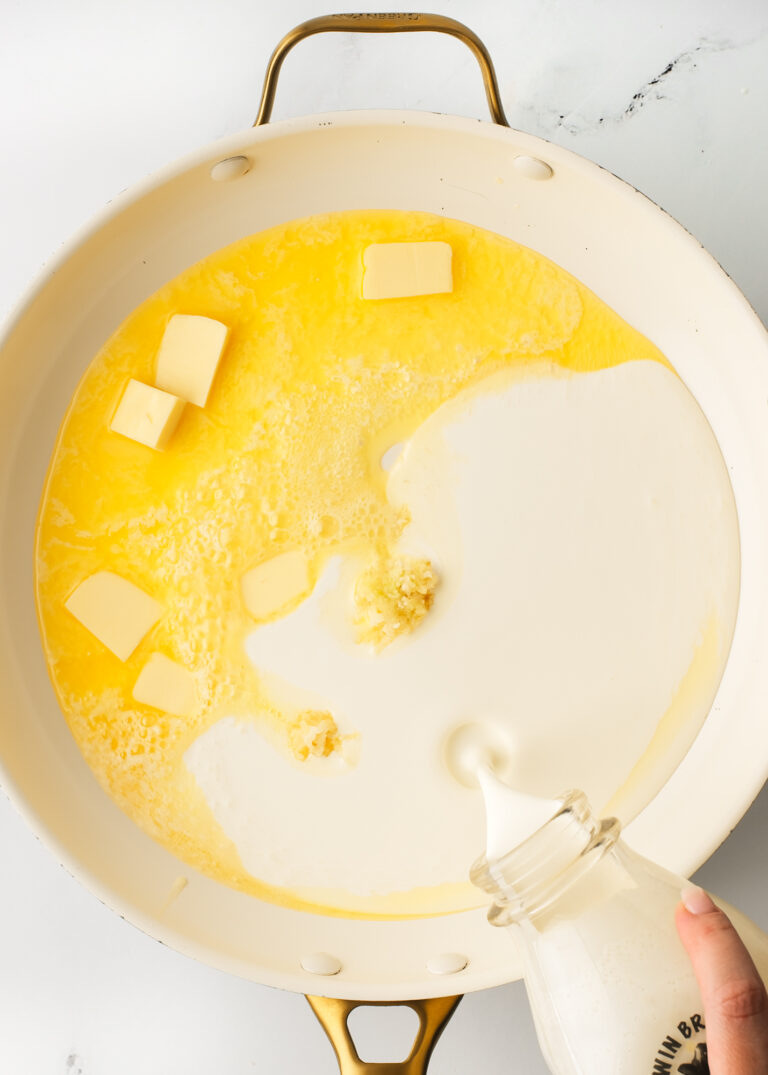 Pouring cream in saucepan with butter.