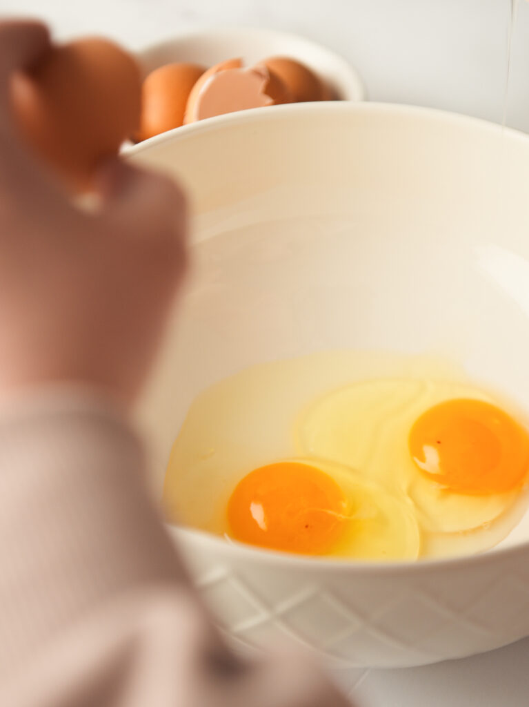 Cracking eggs in large mixing bowl.