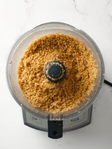 Finely ground walnuts inside food processor.