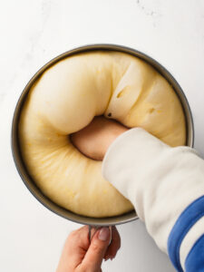 Punching down proofed dough and exposing bubbles.