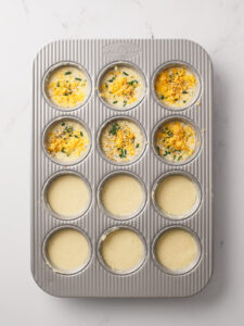 Popover batter in muffin pan with toppings.