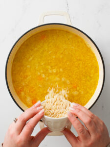 Pouring orzo in soup pot.