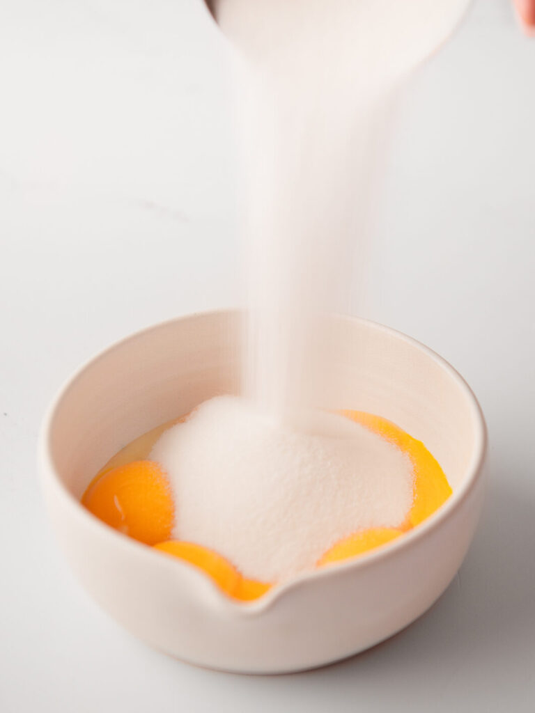 Egg yolks and sugar in a mixing bowl.