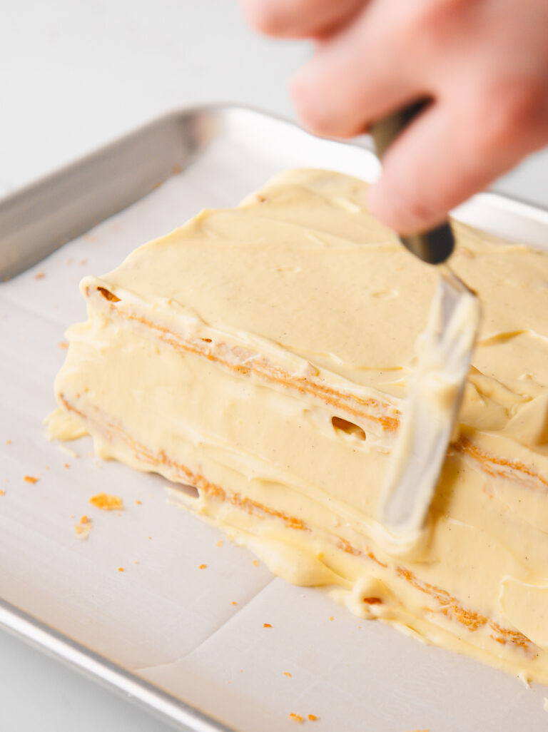 Spreading cream on the outside of the cake.