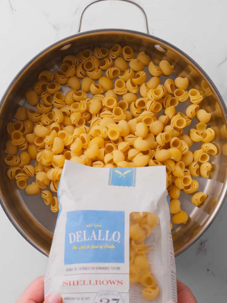 Pouring pasta into pan.