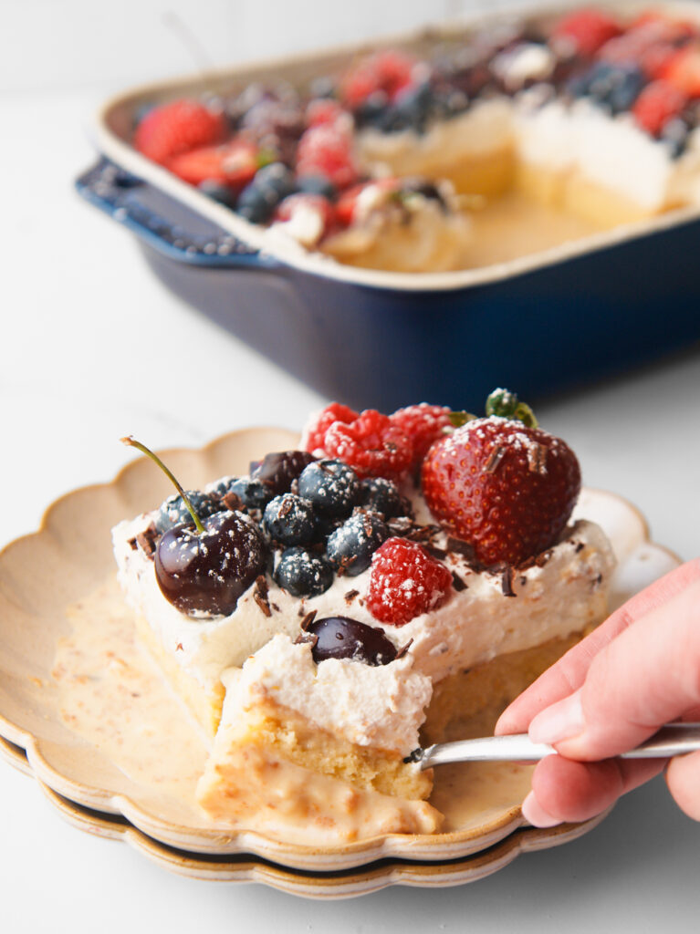 Tres Leches Cake in small plate with entire cake in background.