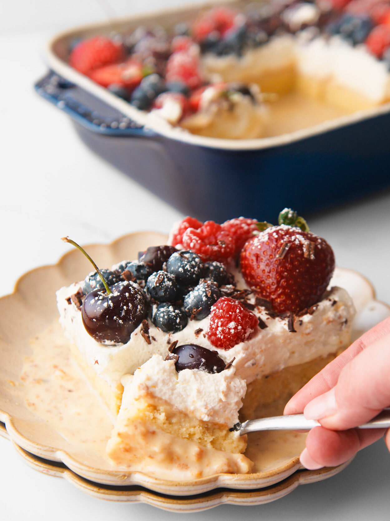 Tres Leches Cake in small plate with entire cake in background.