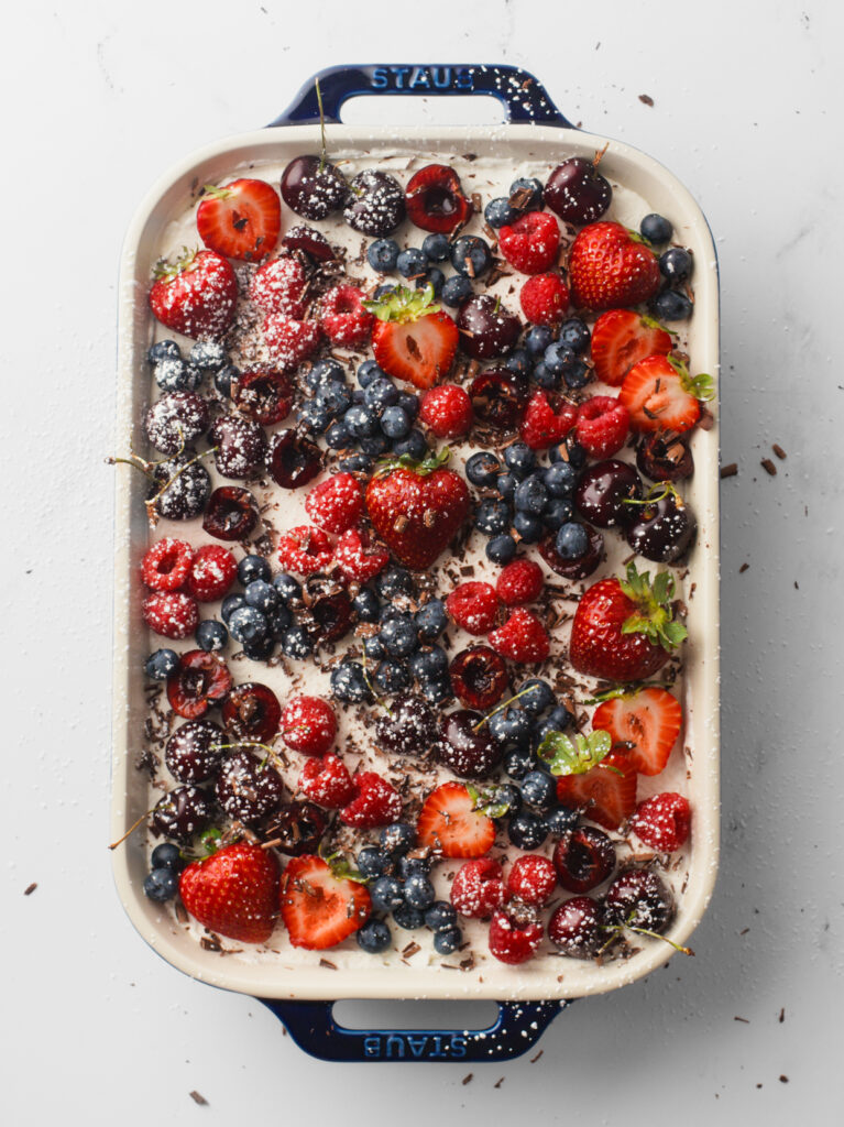Tres Leches Cake garnished with fruit, chocolate shavings and powdered sugar.