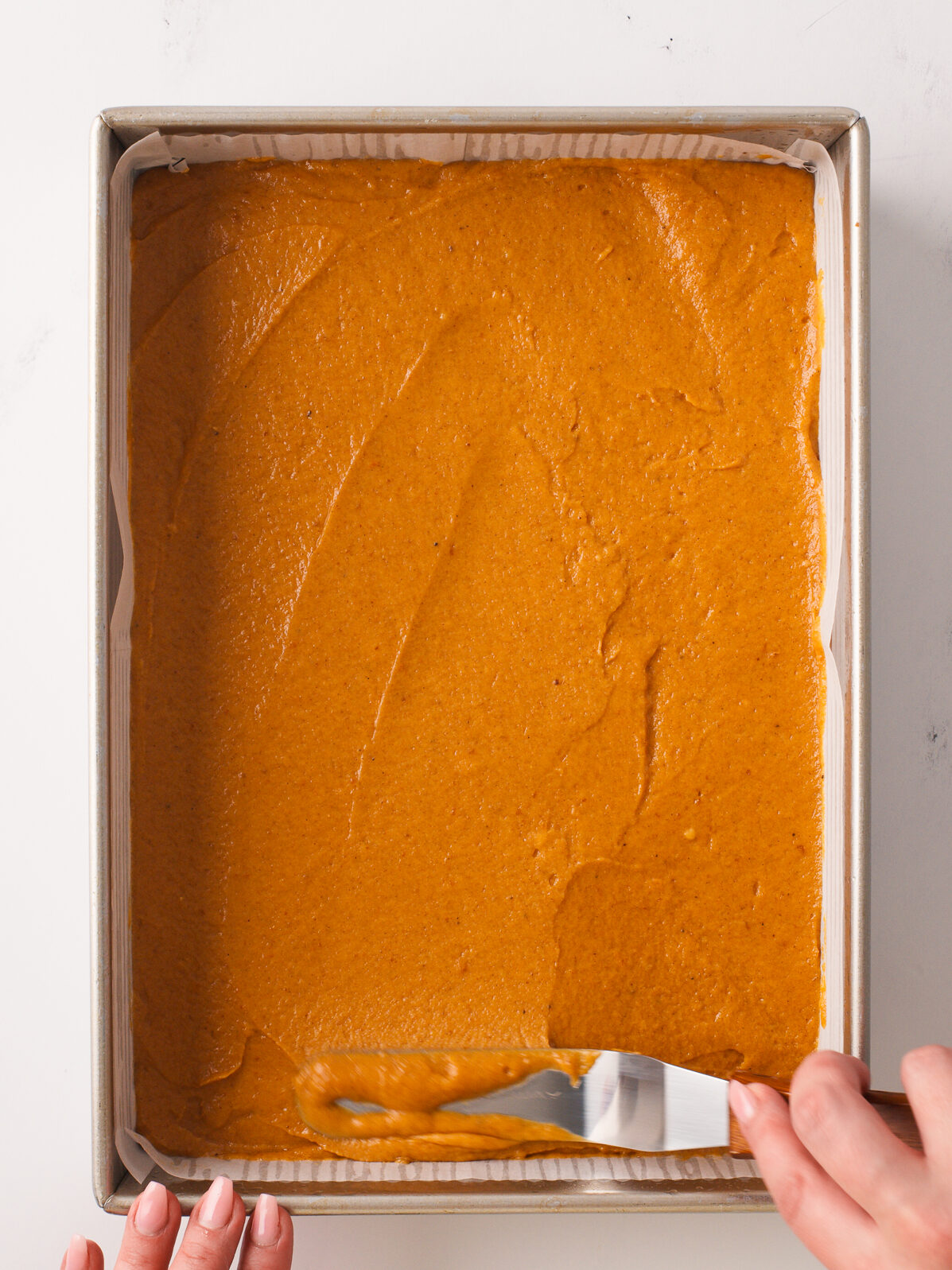 Spreading cake batter in baking pan.