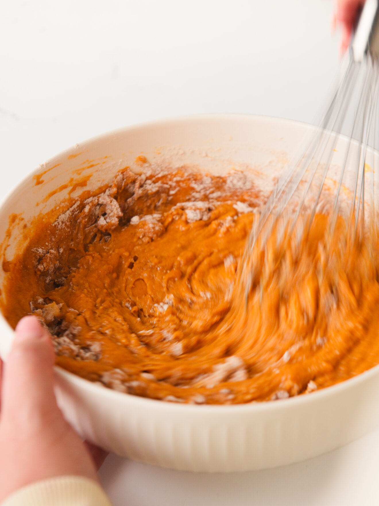 Whisking pumpkin cake batter in bowl.