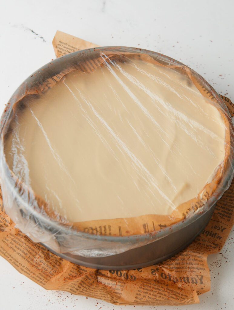 Cake with pan wrapped in plastic wrap.