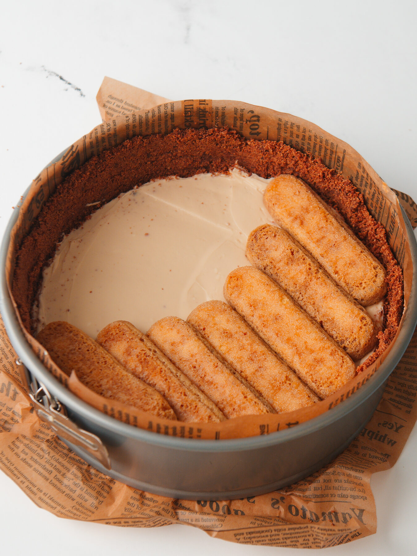 Arranged ladyfingers on top of cheesecake filling.